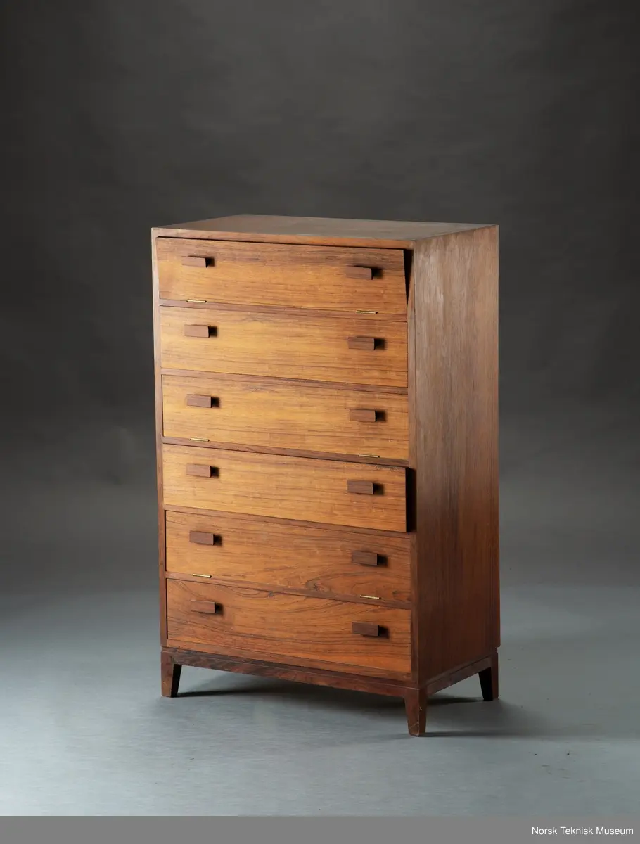 Kommode med skuff tilpasset kretskort. 
Kommoden inneholder permer med manualer, kretskort, esker med hullkortremser, og løse hullkortremser, skruer samt andre løse deler som sikringer, deler til kretskort. 