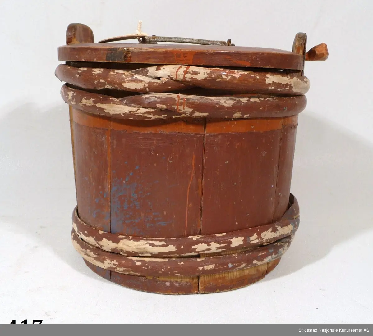 Smørdall i lagget nåletre med fire vidjebånd av bjørk, sylindrisk form. Dallen er malt i en brunrød farge, innskrift i svart.

På lokket er det festet et håndtak av sinktråd. Lokket holdes fast med en "løs" treplugg. Denne festes gjennom hull i ene øret. 
Samme øre er reparert med ei sinkplate pga av slitasje. Initialer og årstall er malt på lokket, under dallen er det ei passer rose, samt merket: PISF.
