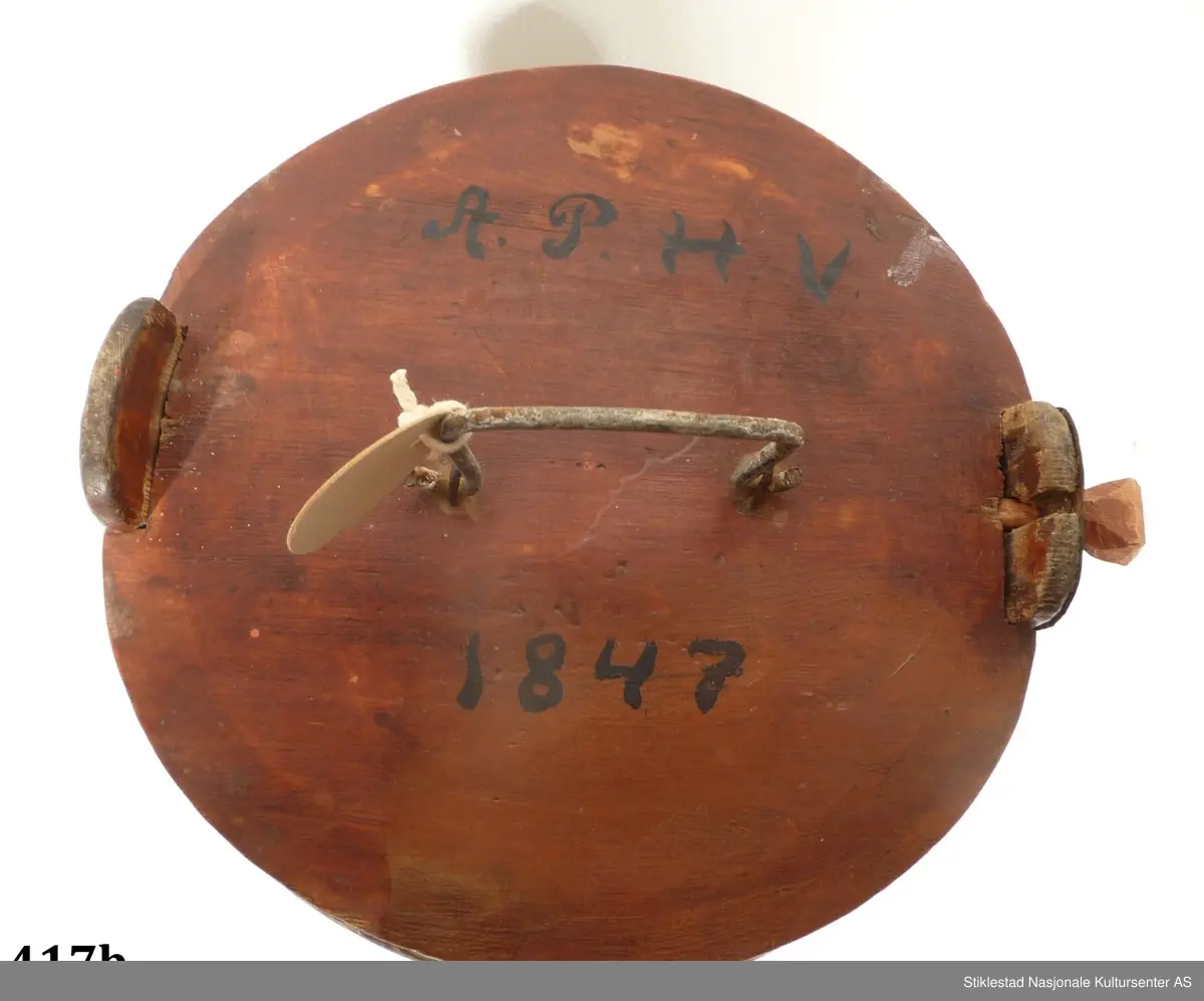 Smørdall i lagget nåletre med fire vidjebånd av bjørk, sylindrisk form. Dallen er malt i en brunrød farge, innskrift i svart.

På lokket er det festet et håndtak av sinktråd. Lokket holdes fast med en "løs" treplugg. Denne festes gjennom hull i ene øret. 
Samme øre er reparert med ei sinkplate pga av slitasje. Initialer og årstall er malt på lokket, under dallen er det ei passer rose, samt merket: PISF.