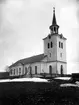 Nya kyrkan. Före branden 1916. På 1860-talet beslöt församlingen att bygga en ny kyrka något ifrån den medeltida kyrkan. Byggmästare var P. Nordin från Trönö i Hälsingland och P.O Hillgren från Gästrikland. Kyrkan består av ett stort långhus och torn i väster där ingången finns. Väggarna är vitputtsade och taket tegelklätt. Tornhuven är klädd med kopparplåt. långhuset har tunnvälvt tak. 1916 skadades kyrkan av ett blixtnedslag. Tornspiran antändes och endast murarna återstod efter branden. Kyrkan återuppbyggdes något förändrad med A Thurdin från Härnösand som arketekt. Kyrkan återinvigdes 1919.