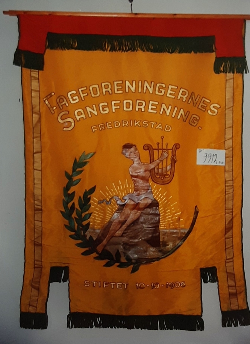 Forside: tekst, person m/lyre gren m/blad. 
Bakside: tekst, lyre og krans