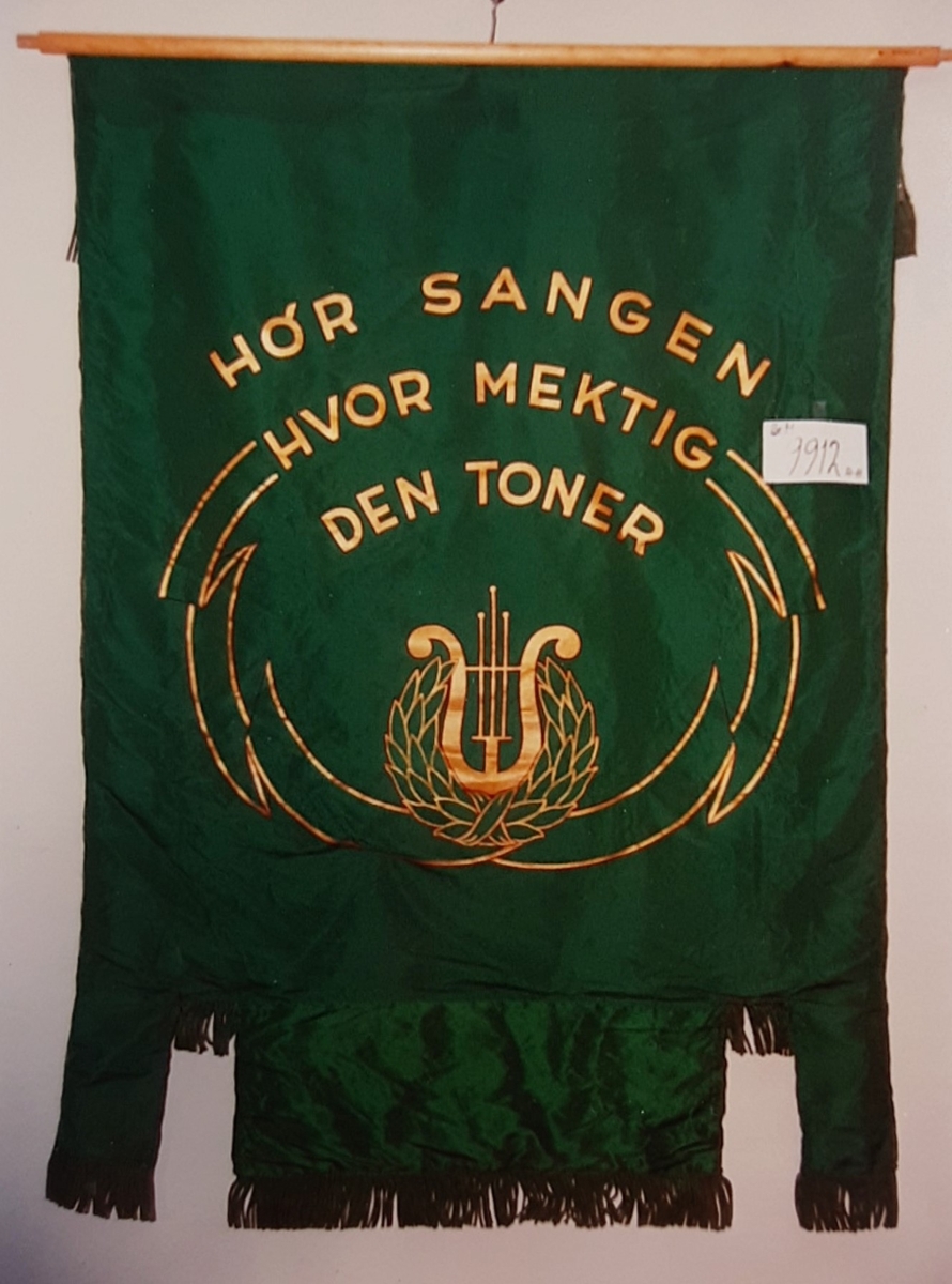 Forside: tekst, person m/lyre gren m/blad. 
Bakside: tekst, lyre og krans