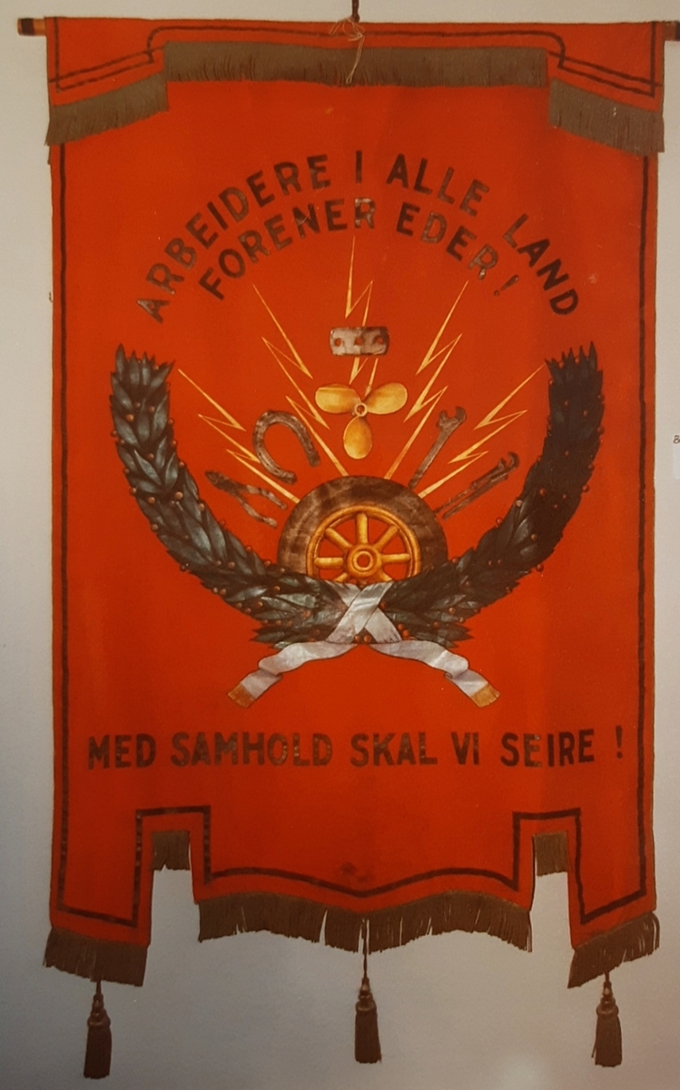 Tekst, to menn i håndtrykk, bormaskin, border (forside) krans og redskaper (bakside)