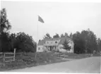 En större putsad byggnad med balkong ovan en entré.