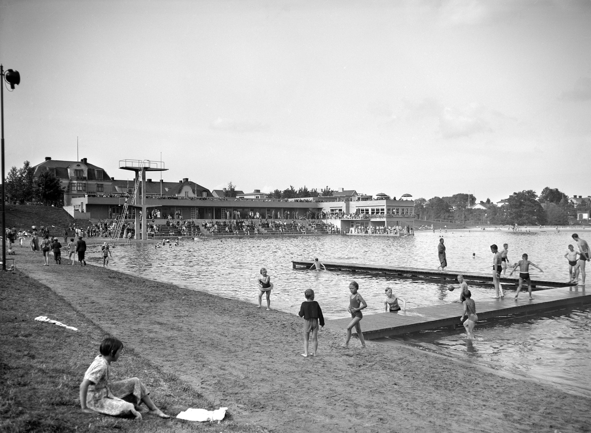 Vy över Tinnerbäcksbadet i Linköping 1938. Det är badets första sommar, tillkommet efter lång diskussion med starka inslag av kritik kring de uttjänta och ohygieniska kallbadhusen i Stångån. Anläggningens slutliga utformning skapades av stadsarkitekten Sten Westholm. Den tidstypiska entré-, omklädnads- och restaurangbyggnaden är i stort ännu orörd sedan den uppfördes. Den drivande politiska kraften bakom badet var köpmannen Axel Brunsjö. I vissa kretsar kallades badet för Brunsjön, efter köpmannens stora engagemang för badet. Badet fick sitt namn efter Tinnerbäcken som före anläggningens tillkomst runnit genom området.