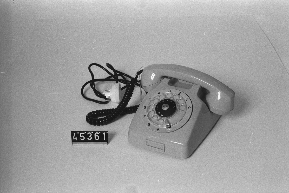 Telefonapparat Dialog för AT-system, huvudapparat, anknytningsapparat till växel och sidoapparat. Bordsmodell av grå termoplast med transparent fingerskiva, extra stora siffror utanför skivan. Svart apparatsnöre. Ringsignalens styrka är ställbar med ett reglage på apparatens undersida.