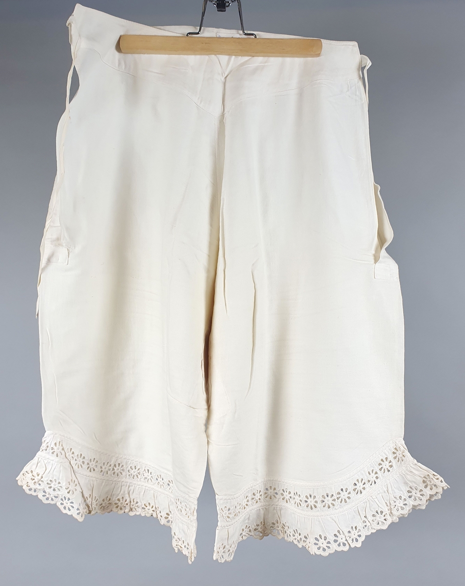 Seks like mamelukker av bomull, med blondekanter på begge ben. Åpning i sidene med knytebånd i linningen. Brodert monogram "A" i linningen. Mamelukkene er i ulik grad slitt og lappet.
