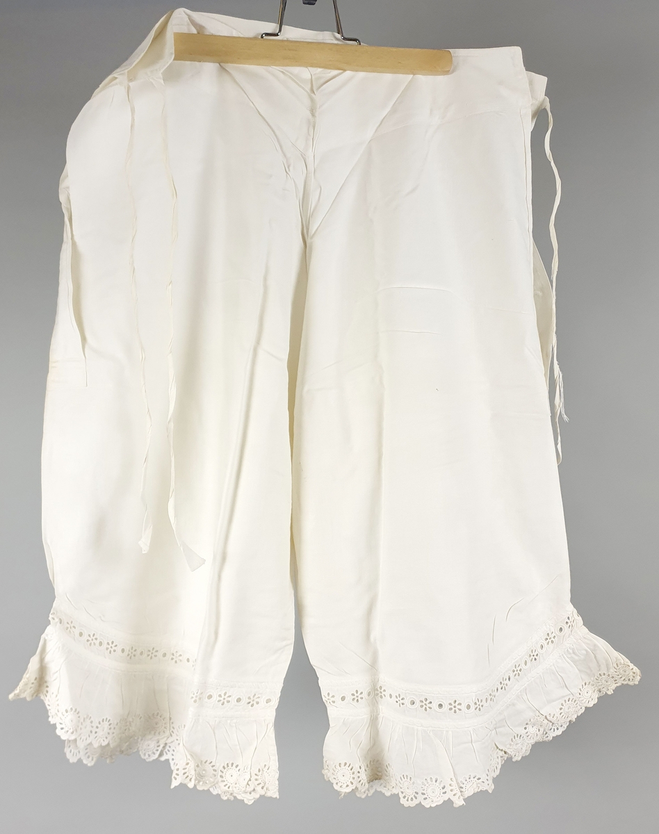 Seks like mamelukker av bomull, med blondekanter på begge ben. Åpning i sidene med knytebånd i linningen. Brodert monogram "A" i linningen. Mamelukkene er i ulik grad slitt og lappet.