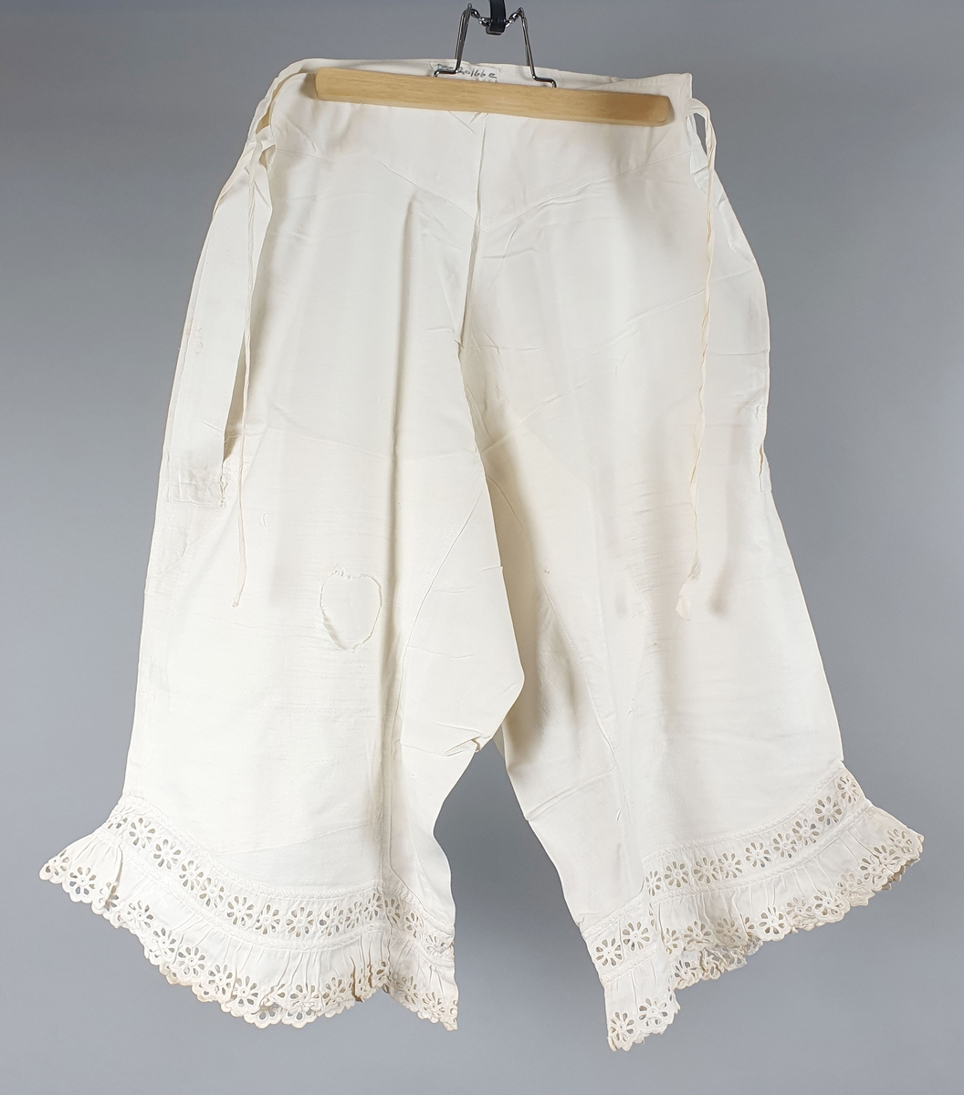 Seks like mamelukker av bomull, med blondekanter på begge ben. Åpning i sidene med knytebånd i linningen. Brodert monogram "A" i linningen. Mamelukkene er i ulik grad slitt og lappet.