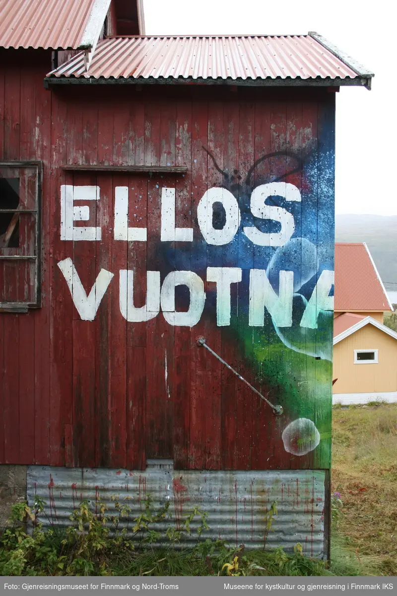 Protestleiren på Markoppneset i Finnmark i 2021. Protestbevegelsen mot dumping av gruveavfall i Repparfjorden har samlet seg og har etablert en teltleir. Bildet er del av en serie som dokumenterer leiren og omgivelsen i området.
Bildet på naustveggen er et verk av kunstneren Tegson og har tittelen "Ellos vuotna".