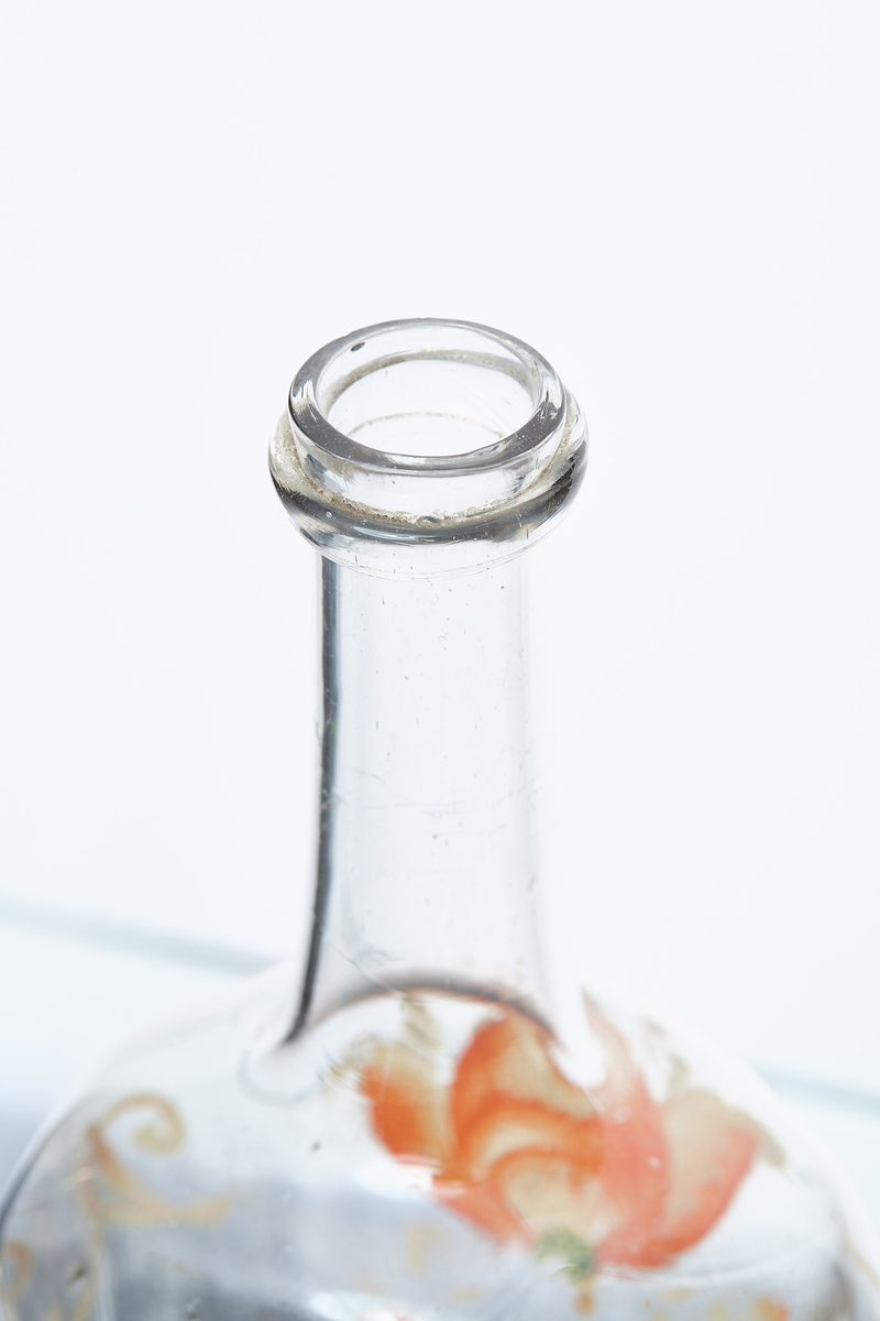 Blåst karaffel i blankt glass. Brutt puntelmerke i bunnen. Påmalt blomsterdekorasjon, med årstallet 1732 og bokstavene JT og DR. 1732 antas å være fødselsåret til eieren, da denne flasketypen kom seinere. 
