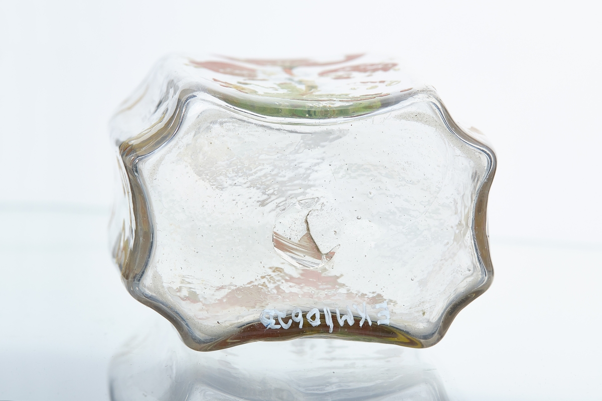 Blåst karaffel i blankt glass. Brutt puntelmerke i bunnen. Påmalt blomsterdekorasjon, med årstallet 1732 og bokstavene JT og DR. 1732 antas å være fødselsåret til eieren, da denne flasketypen kom seinere. 
