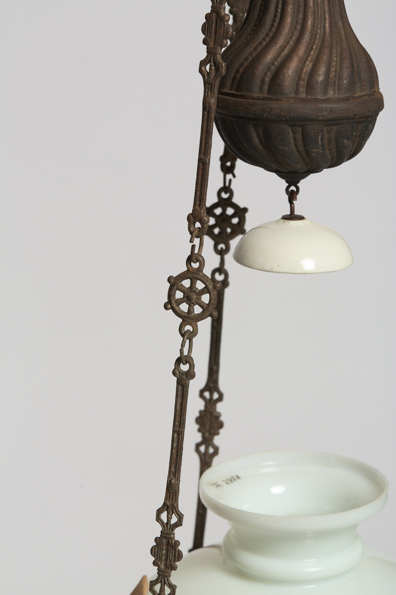 Heisbar parafinlampe ombygd for elektrisitet. Fra Høgbakken. Enkelstående med kuppel bunn i hvit porselen.  Det stikker ut ett tau ut av midten.