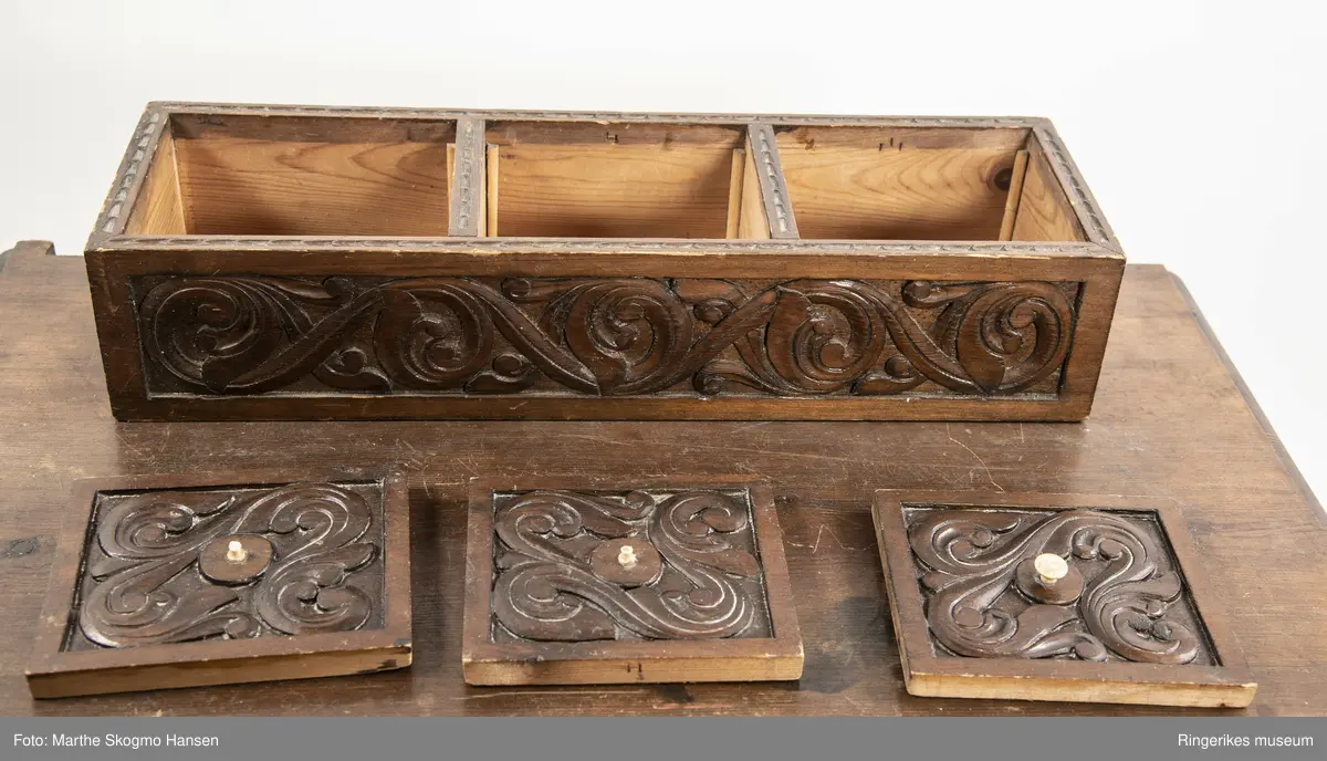 LIte bord med to skuffer og en boks på toppen. Fronten på skuffene, sidene på bordet, og boksen på toppen er skåret ut i tradisjonelt norsk akantusranke-mønster. Beina er skåre ut med geometriske mønstre på alle sider. Bordplata har en øvre del med rette kanter, men så buer den seg utover, så undersiden av bordet er større enn oversiden. Skuffene har håndtak av metall. Boksen er delt i tre rom med lokk. Lokkene er også skåret ut i samme mønster. De løftes ved hjelp av små håndtak, muligens av elfenben. To av disse er ødelagte. Boksen har helt tydelig vært festet i bordet, det er spor etter festene på hver side av boksen, og på baksiden av bordet er det skåret inn to hakk, et på hver side av boksen, disse er ca. 7 cm brede. I hver av disse hakkene står en bøyd, rusten spiker. På høyre side, sett forfra, har den biten av bordet som skulle vært på utsiden av hakket forsvunnet. Siden festet har blitt borte, er boksen nå løs. 