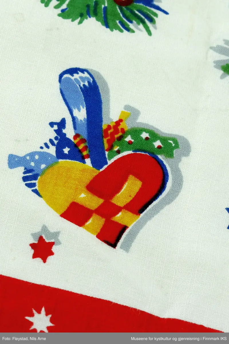 En rektangulær juleløper av bomull med maskinsøm langs kantene og trykt motiv. Duken har to røde dekorkanter med hvite stjerner på langsidene av duken. Motivet på duken består av små blå og røde stjerner og grønne grener med røde bær, i tillegg til bjeller, et hus, en lykt engler, en stor stjerne og en skål med grøt oppi helt i ene enden av duken. Fargene på duken er hvit, rød, grønn, gul og blå. 