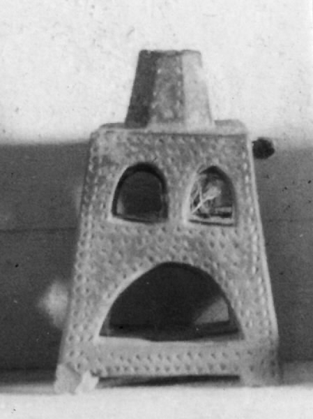 Ljusstake av bränt lergods. Fyrkantig, med öppningar med rundbågar. Ljushållare för ett ljus.