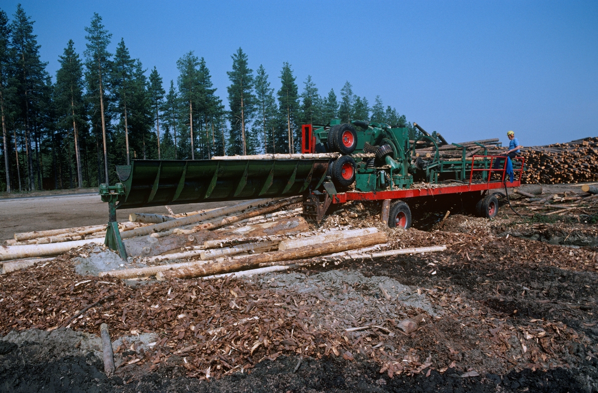 Fra Glomma fellesfløtingsforenings «vassdragsterminal»  eller «tømmerterminal» Terningvelta, på vestsida av Glomma i Elverum kommune i Hedmark. Fotografiet ble tatt i 1980. Her ser vi en maskin tømmeret ble kjørt gjennom (fra høyre mot venstre på dette bildet) for å fjerne barken. Her ser det ut til at stokkene ble trukket gjennom maskinen mellom langsomtroterende gummihjul. Samtidig passerte stokkene antakelig roterende piggvalser, som rev løs barken. Dette ble gjort dels fordi tømmeret skulle få en forsiktig tørk før det ble slått på vannet, hvor det helst skulle flyte til det nådde industrien nederst i vassdragene. For papirindustrien var det viktig at barken var borte, for ellers fikk man mørke flekker i papirmassen. Barkemaskinene var altså mobile, og kunne flyttes mellom termialene. Glomma fellesfløtingsforening og Glommen cellulosetømmerkjøperes forening inngikk den første avtalen om maskinbarking med Mjøsen og Glommen skogeierforening i 1966.

Vassdragsterminalene var store, bulldoserplanerte tømmeropplagsplasser der fløtingsvirke ble levert med lastebiler gjennom driftssesongen i vinterhalvåret. De store virkesvolumene som ble levert ved hver av disse terminalene åpnet for mekanisering av barkinga og for maskinelt utislag når fløtingssesongen startet. Disse anleggene oppsto som en konsekvens av at det ble bygd et vidgreinet nett av skogsbilveger i de første to-tre tiåra etter 2. verdenskrig. Det viste seg at det ble billigere å hente fløtingsvirket med lastebiler fra ved disse vegene enn å organisere det arbeidet som måtte til for å transportere det med det rennende elvevannet. Terminalene ved hovedvassdragene ble altså bygd da fløtingsaktiviteten i mange av de over 100 mer eller mindre vanskelig fløtbare sideelvene ble avviklet i 1960-åra. Det var de regionale fløtingsinspektørene som gjorde avtaler med transportører som kjørte fløtingsvirket fra velter langs skogsbilvegene til hovedvassdraget. Vassdragsterminalene ble anlagt av Glomma fellesfløtingsforening i samarbeid med Glommens Tømmermaaling. Fellesfløtingsforeningen tok vanligvis 75 prosent av opparbeidings- og vedlikeholdskostnadene, og betalte naturligvis for det maskinelt utstyr og arbeidskraft på vassdragsterminalene. Også for tømmermålerne innebar lastebilleveransene av tømmer ved vassdragsterminalene effektiviseringsmuligheter. Ettersom det stort sett var «slipvirke» - cellulosevirke med lavere verdi enn «sagtømmeret» som skulle bli skurlast – som ble fløtet fra terminalene, tillot de seg å foreta lassmålinger i stedet for å måle hver enkelt stokk. Ifølge et kart Glomma fellesfløtingsforening fikk utarbeidet på den tida dette fotografiet ble tatt hadde organisasjonen 46 terminalplasser ovenfor Glommas møte med Vorma på Øvre Romerike.