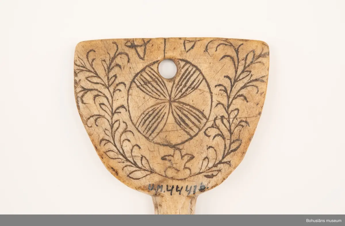 Rund pinne med triangulärliknande platta upptill. På en av sidorna finns ristad och svärtad dekor bestående av två korsade bladslingor med en rosett i mitten.
Baksidan har mörknat på grund av användning.

Ur handskrivna katalogen 1957-1958:
Två selpinnar av ben
b) Mått: 16,7 x 7,5 cm; form som föreg; dekoren har rankor och en stiliserad blomma. Hel.

Svar på förfrågan kring föremålen UM003945, UM004440, UM004441, UM004442 till Ajttemuseet, Jokkmokk januari 2007, som skriver:
Vi uppfattar inte föremålen som direkt samiska, inte heller i gravyren. Visst har det funnits bofasta samer, så det kan vara möjligt, men ofta hade de också renar för transport. 
Enligt Stig Harry Johansson, Tärnaby som besökte museet 17/3 1988 är föremålet tillverkat av horn från älg eller ren.

Lappkatalog: 40

Litt.; Nylén, Anna-Maja, Hemslöjd, Håkan Ohlssons förlag, Lund, 1978, s. 396-401.