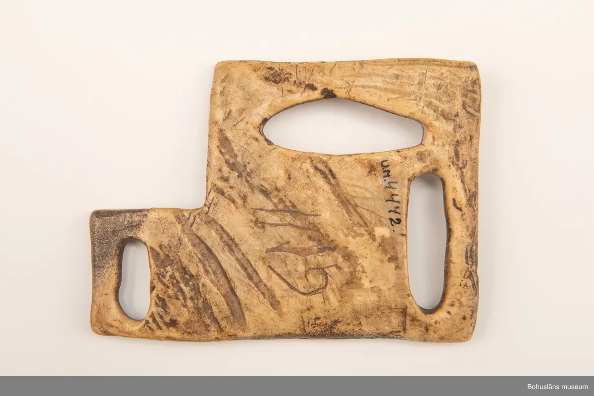 Skiva med tre avlånga urtag att fästa remmar i.
Mittpå en av sidorna är siffrorna "1119" inristade (kan vara år-talet "1779"?).
Har mörknat på grund av användning.

Ur handskrivna katalogen 1957-1958:
Remskiva av ben (för seldon)
Mått: 15,5 x 11 cm; (teckning) 3 fästen f. remmar; "1119". Hel.

Svar på förfrågan kring föremålen UM003945, UM004440, UM004441, UM004442 till Ajttemuseet, Jokkmokk januari 2007, som skriver:
Vi uppfattar inte föremålen som direkt samiska, inte heller i gravyren. Visst har det funnits bofasta samer, så det kan vara möjligt, men ofta hade de också renar för transport. 
Enligt Stig Harry Johansson, tärnaby som besökte museet 17/3 1988 är föremålet tillverkat av älg eller renhorn.

Lappkatalog: 40

Litt.; Nylén, Anna-Maja, Hemslöjd, Håkan Ohlssons förlag, Lund, 1978, s. 396-401.