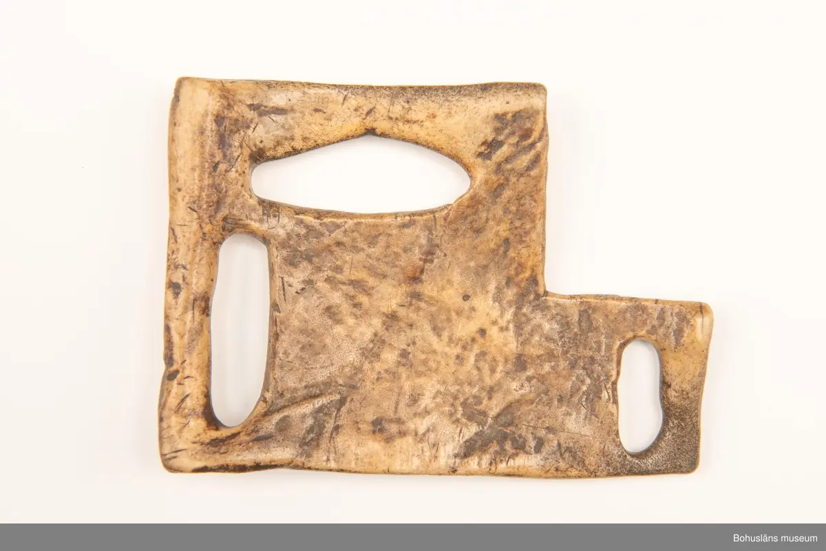 Skiva med tre avlånga urtag att fästa remmar i.
Mittpå en av sidorna är siffrorna "1119" inristade (kan vara år-talet "1779"?).
Har mörknat på grund av användning.

Ur handskrivna katalogen 1957-1958:
Remskiva av ben (för seldon)
Mått: 15,5 x 11 cm; (teckning) 3 fästen f. remmar; "1119". Hel.

Svar på förfrågan kring föremålen UM003945, UM004440, UM004441, UM004442 till Ajttemuseet, Jokkmokk januari 2007, som skriver:
Vi uppfattar inte föremålen som direkt samiska, inte heller i gravyren. Visst har det funnits bofasta samer, så det kan vara möjligt, men ofta hade de också renar för transport. 
Enligt Stig Harry Johansson, tärnaby som besökte museet 17/3 1988 är föremålet tillverkat av älg eller renhorn.

Lappkatalog: 40

Litt.; Nylén, Anna-Maja, Hemslöjd, Håkan Ohlssons förlag, Lund, 1978, s. 396-401.