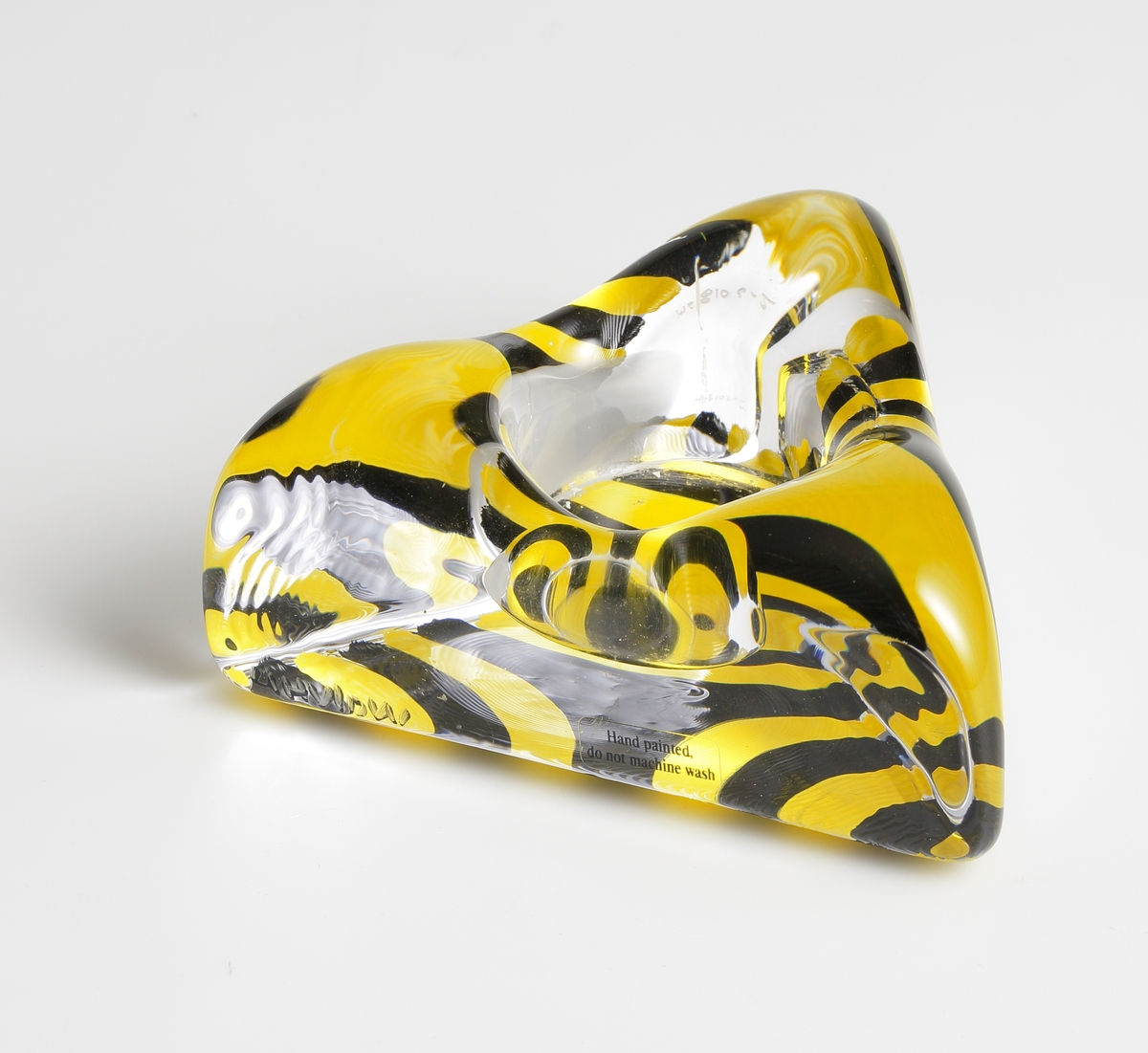 "Piece of Cake" formgiven av Ulrica Hydman Vallien. Trekantig ljusstake för värmeljus. Botten målad i svart och gult.
