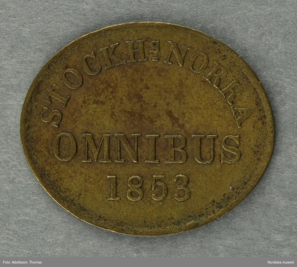 Huvudliggaren:
"a-c, Polletter, 3 st, prägladen mässing, oval; inskr. 'Stockhs Norra Omnibus 1853'.
G. 22/9 1939 av fröken Julie Lohrmans sterbhus, Stockholm."