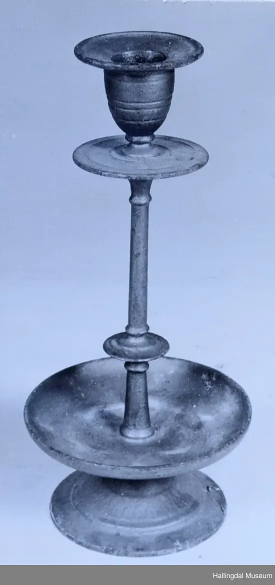 Sirkulær fotring, skrår opp mot stett med sirkulært tverrsnitt. Dryppskål like over fotring, opphøyd kant. To sirkulære skiver rundt stett, den ene like under pipen. Pipen har buet side mot stett. Krage skrår svakt oppover. Profiler.
23/6-67 O. Foldøy.