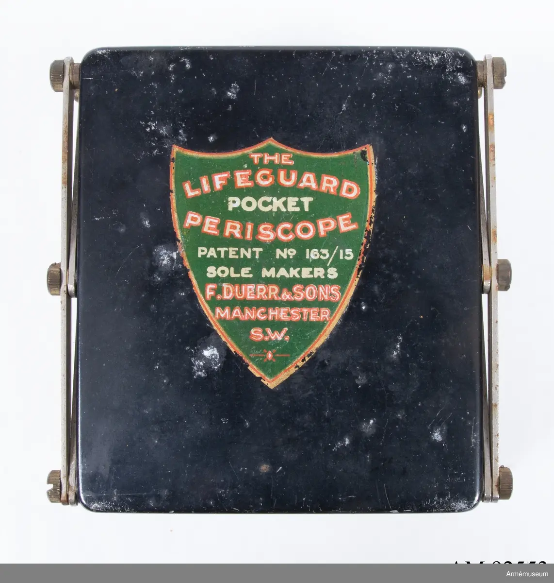 Saxmodell. Material: Målad metall, mässing och spegelglas. Etikettmärkt ”THE LIFEGUARD POCKET PERISCOPE. PATENT No. 163/15 SOLE MAKERS F. DUERR & SONS, MANCHESTER, S.W.” Storbritannien, Första världskriget.