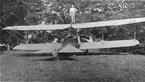 Flygplan Albatros B.IIa nr 6 tillhörande Flygkompaniet uppställt på ett fält, 1916. En man står på övervingen. Vy bakifrån.