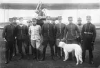 Grupporträtt av elva militärer och en hund framför flygplan på ett fält, omkring 1920. Från vänster Knut Zackrisson, okänd, okänd, okänd, okänd, Georg Gärdin, okänd, okänd, okänd, Ferdinand Cornelius, okänd.