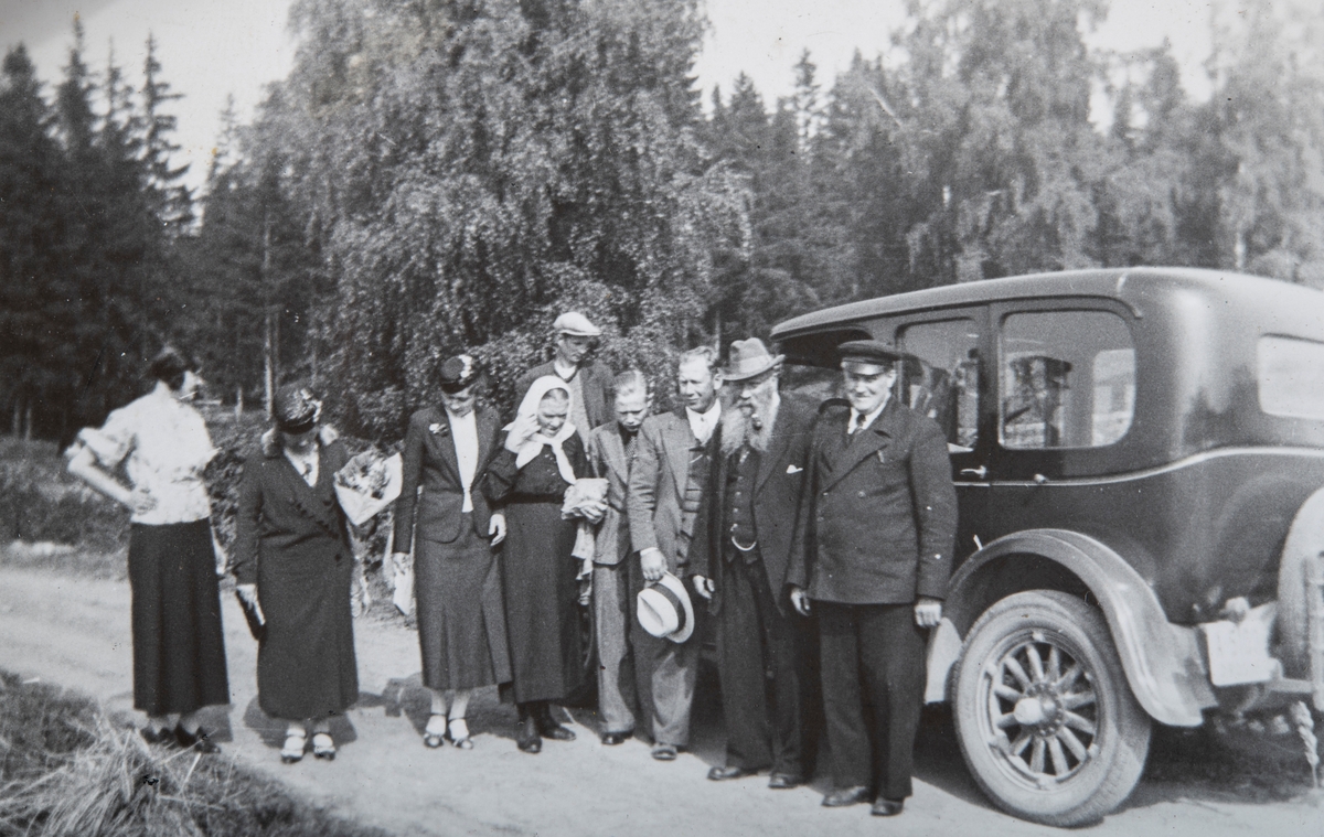 Klare for en biltur til Eidsvoll for å besøke en slektning. Fra venstre: Anna Andersen Nygård, Helga Smeby,  Anna Olsen, Pauline Fuglesang, Ole Martinsen (bak), Arne Smeby, en kamerat av Arne Smeby, Anton Fuglesang og Anton Smeby, som også var sjåfør og bileier. Bildet er tatt på veien ved plassen Fuglesang, i Stange i 1935. Sjåføruniform.