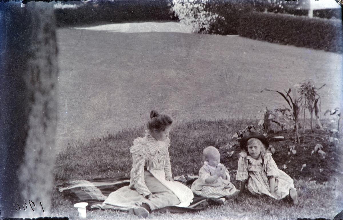 Barnepike Magda Eriksrud fra Toten,  med barna Jacob Hoel og Thora Hoel i hagen på Hovinsholm 1900.