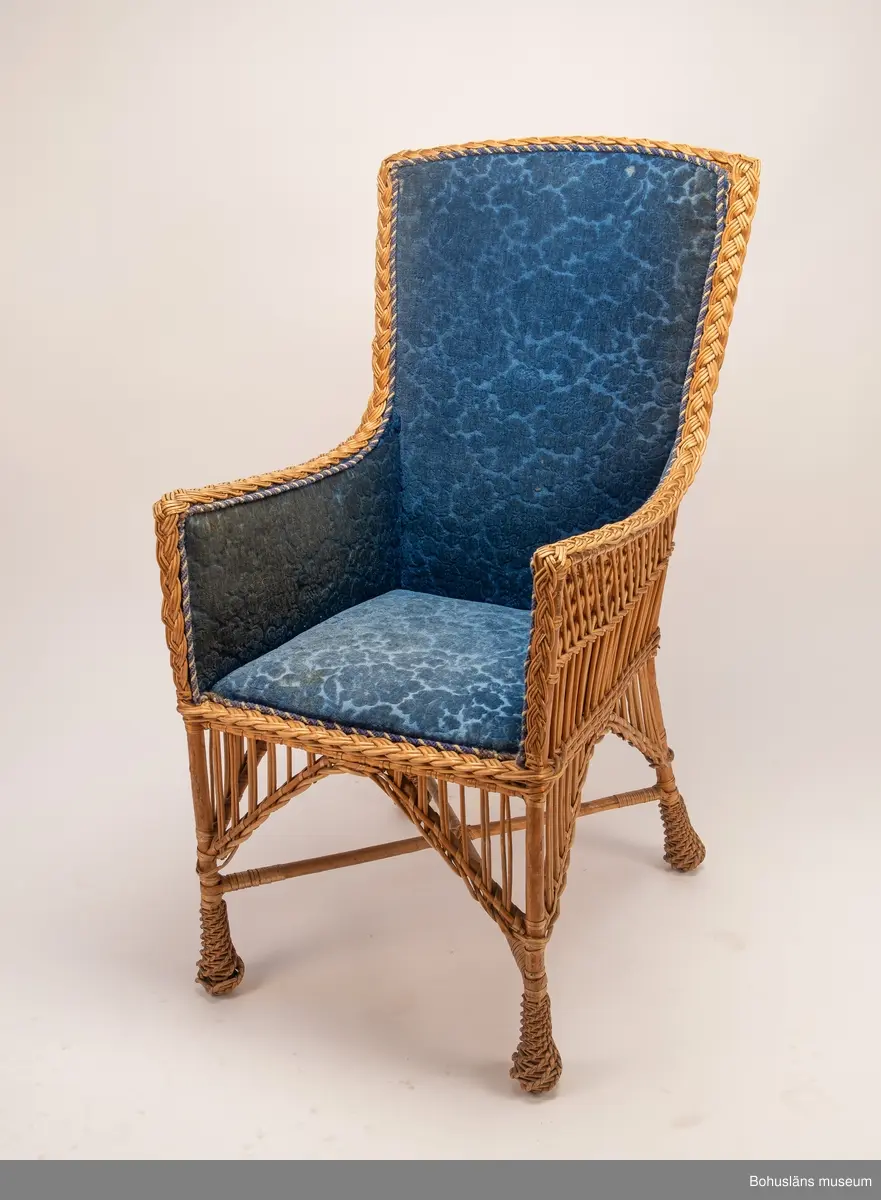 Ur handskrivna katalogen 1957-1958:
Korgstol
H. 117; Br. 59 cm; sits, ryggstöd och armstöd är på "insidan" klädda m. blå, mönstrad plysch. Hel. 
Enligt Brander [Evert Brander, vaktmästare på Uddevalla museum under 1940- och 1950-talen] gjord för Oskar II till Uddevalla - Lelångebanans invigning.