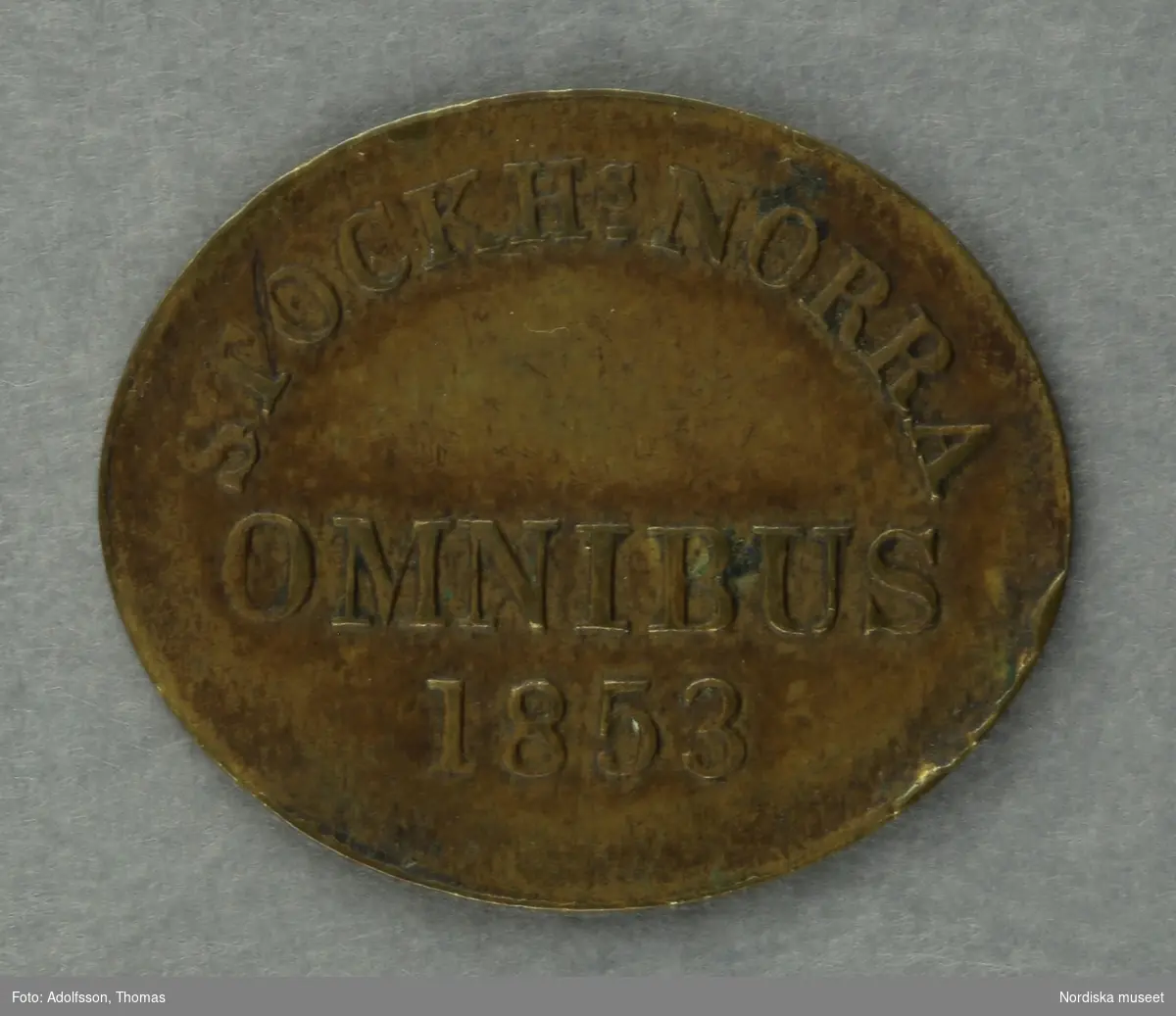 Huvudliggaren:
"a-c, Polletter, 3 st, prägladen mässing, oval; inskr. 'Stockhs Norra Omnibus 1853'.
G. 22/9 1939 av fröken Julie Lohrmans sterbhus, Stockholm."