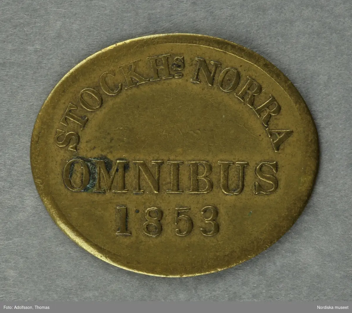 Huvudliggaren:
"a-c, Polletter, 3 st, prägladen mässing, oval; inskr. 'Stockhs Norra Omnibus 1853'.
G. 22/9 1939 av fröken Julie Lohrmans sterbhus, Stockholm."