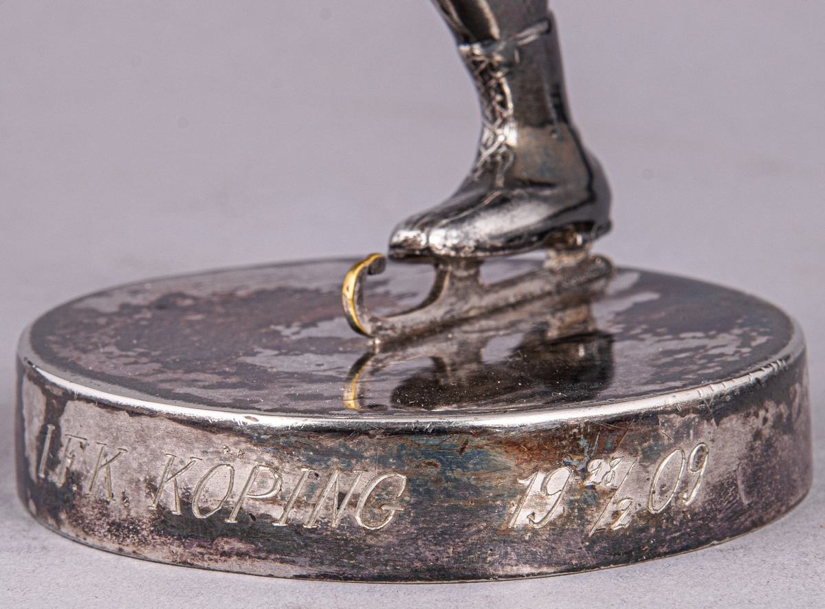 Statyett i nysilver, skridskoåkare. Inskription: IFK Köping. 28/2 1909.