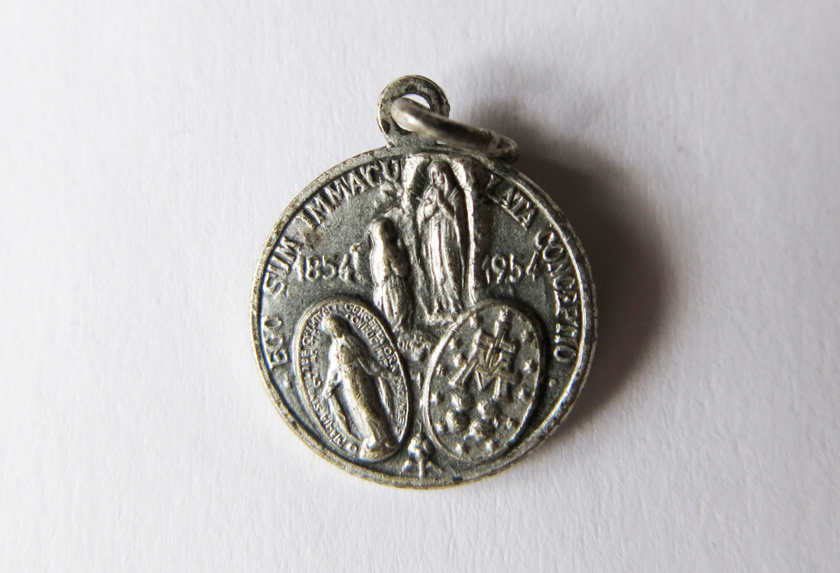 Motiv advers: Pavene Pius IX, Pius X og Pius XII, byster i profil mot venstre.

Motiv revers: Jomfru Maria i Lourdes med knelende Bernadette, nederst den mirakuløse medaljens advers og revers.