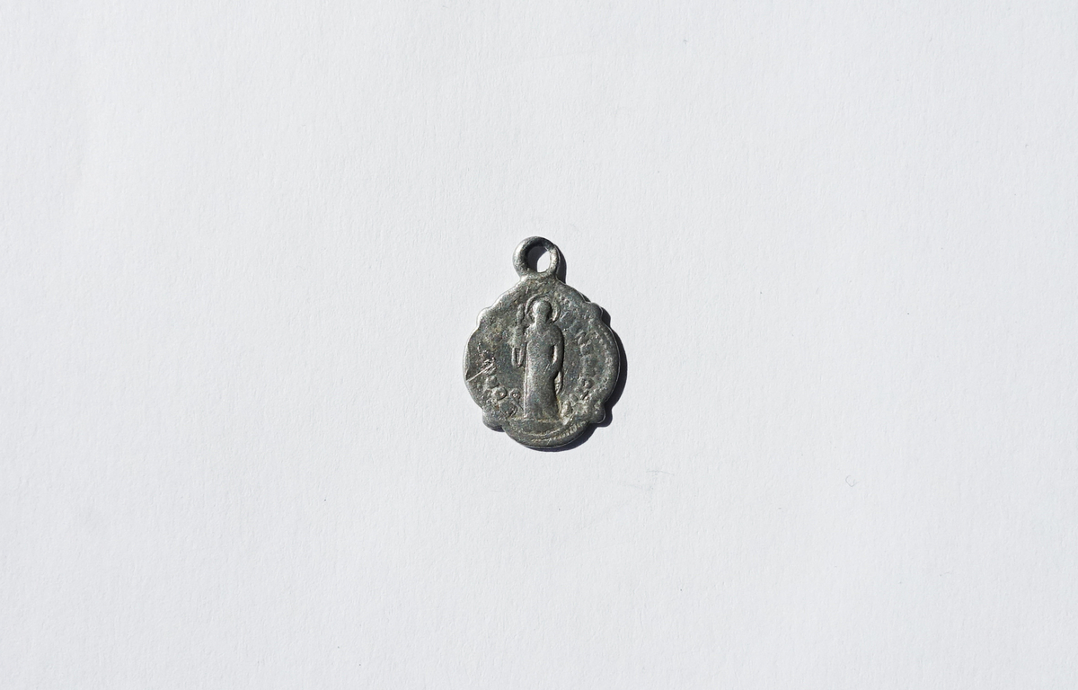 Motiv advers: St. Benedikt i frontal helfigur med stråleglorie i mandorla. Han holder et kors i sin høyre hånd, og sin munkeregel i venstre. Abbedmitra og krumstav ved hans høyre fot og ravn med brødbit i nebbet ved hans venstre.

Motiv revers: Kors med utsveifede armer.
