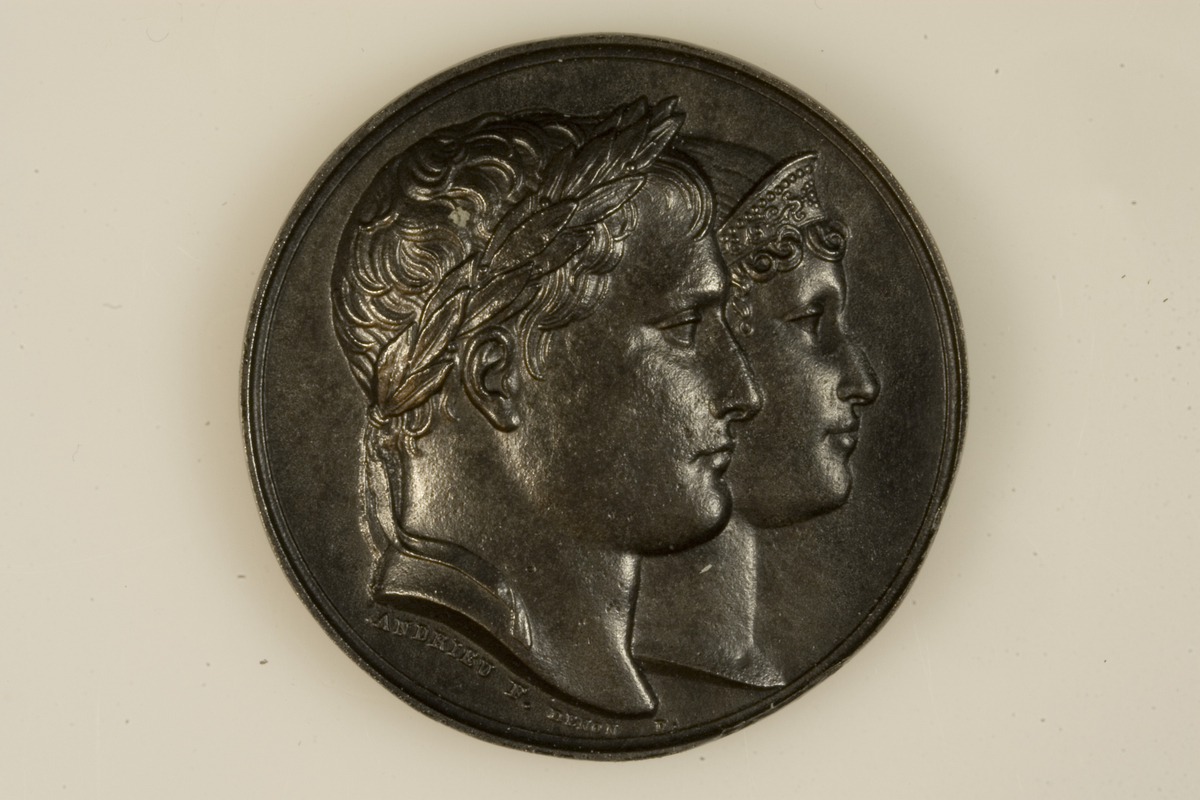 Motiv advers: Napoleon, laurbærkranset, og Marie Louise av Østerrike med diadem, i profil mot høyre.

Motiv revers: Laurbærkranset, antikt kledd Napoleon fører keiserinne Marie Louise hen mot et alter hvorpå det brenner en ild. På alteret to fakler og en bue.