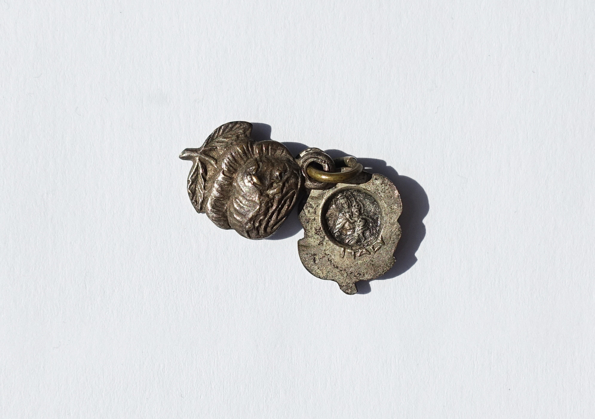 Motiv advers: Lokket: Rose med blader. På baksiden i runding: nonne med roser og krusiks, den hellige Rita av Cascia.
Nederste del: I runding Jomfru Maria i halvfigur, kronet og tronende, med Jesusbarnet på venstre kne, også han kronet. På baksiden rose med blader.

Motiv revers: Rose med blader.