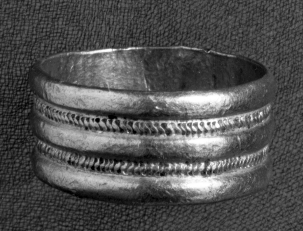 " Iblandt Benene fandtes en Guldfingerring No. 1894 b, delt i tre glatte Baand med mellemliggende riflede Traade (Mont. 353)" Fingerring av gull, Andersson type 11 var. Ia, i samsvar med beskrivelsen. (Andersson nr. 850)