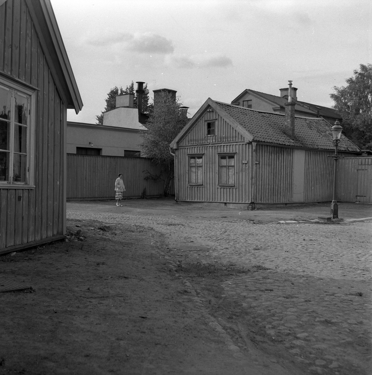 Kerstin Åsén står i en gatukorsning i Jönköping. Längs gatan syns sten- och trähus.