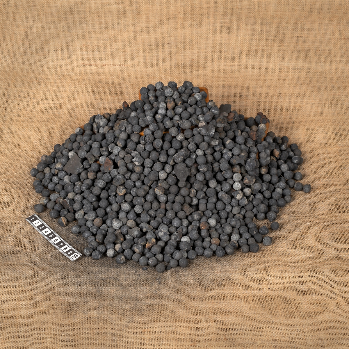 Muskötkulor från kistan, med cementrester (diameter: 10-12 mm, vikt per kula: 6-9 gram, totalvikt: 11.860 kg).
Material: cement och bly
Mått: diameter: 10-12 mm, vikt per kula: 6-9 gram, totalvikt: 11 860 kg