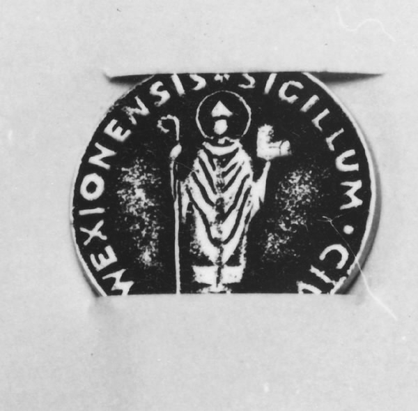 Minnespeng av vitmetall. På framsidan sankte Sigfrids bild och texten SIGILLUM CIVITATIS WEXIONENSIS mot svartanlöpt grund.