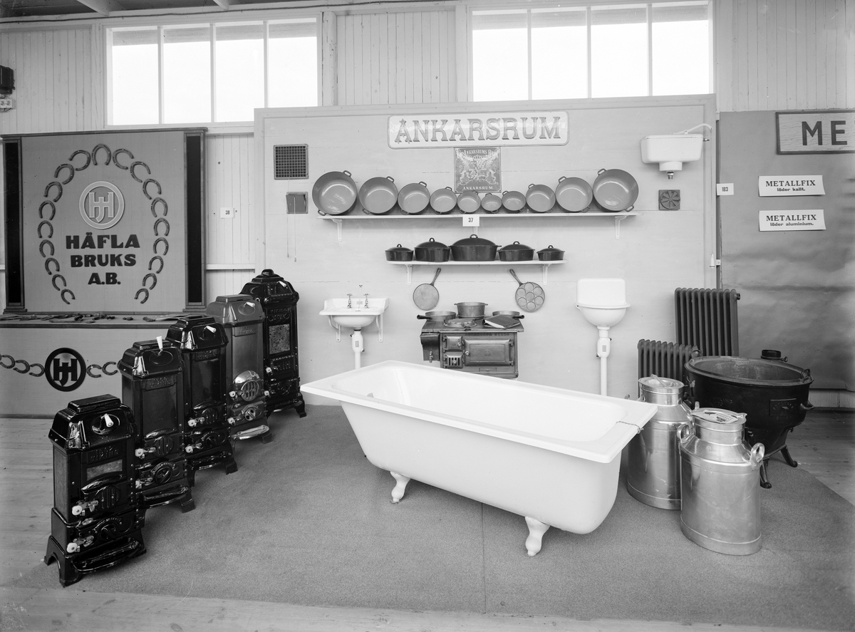 Motiv från jubileumsutställningen i Skänninge 1929. Utställningen var en del i 400-årsjubiléet av de stadsprivilegier som Gustav Vasa utfärdat staden. Östergötlands läns hushållsningssällskap förlade årets länslantbruksmöte hit och en parallell konst-, hantverks- och industriutställning som invigdes av kronprins Gustaf Adolf den 20 juni. På bilden visar Ankarsrums Bruk ett urval av sina produkter.