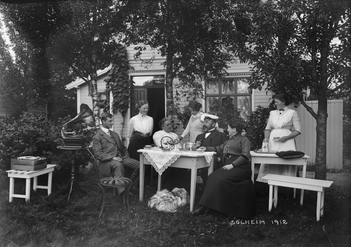 Gruppe ved kaffebord i hage
Fotografert 1912