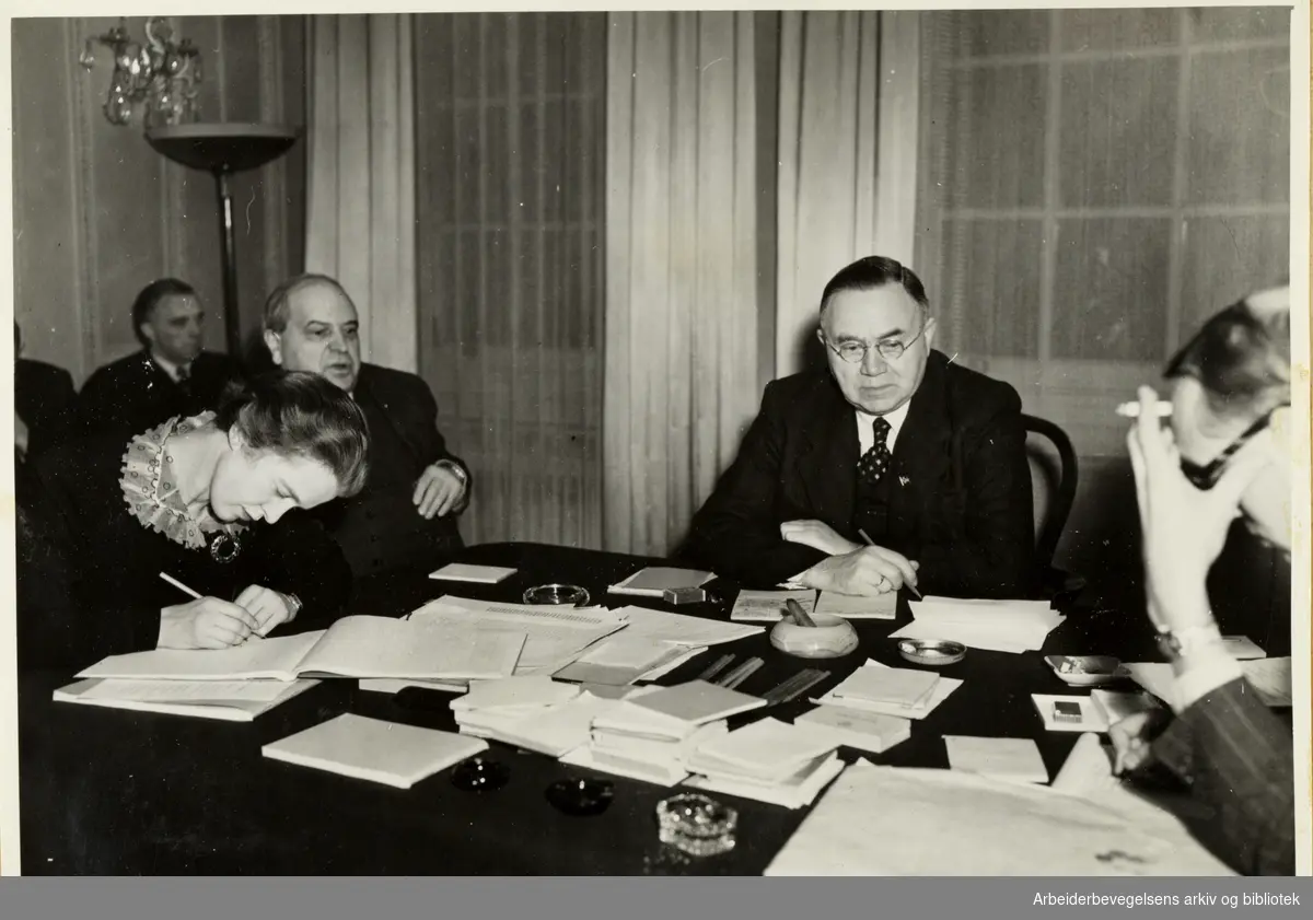 Fra Johan Nygaards Album, Tekst i album: Fra Lilletinget i London 1944. Fra venstre ved bordet: sekretær Rachel Sewerin, Stortingspresident Hambro, Johan Nygaardsvold og Arne Schau. I bakgrunnen statsråd Hjelmtveit