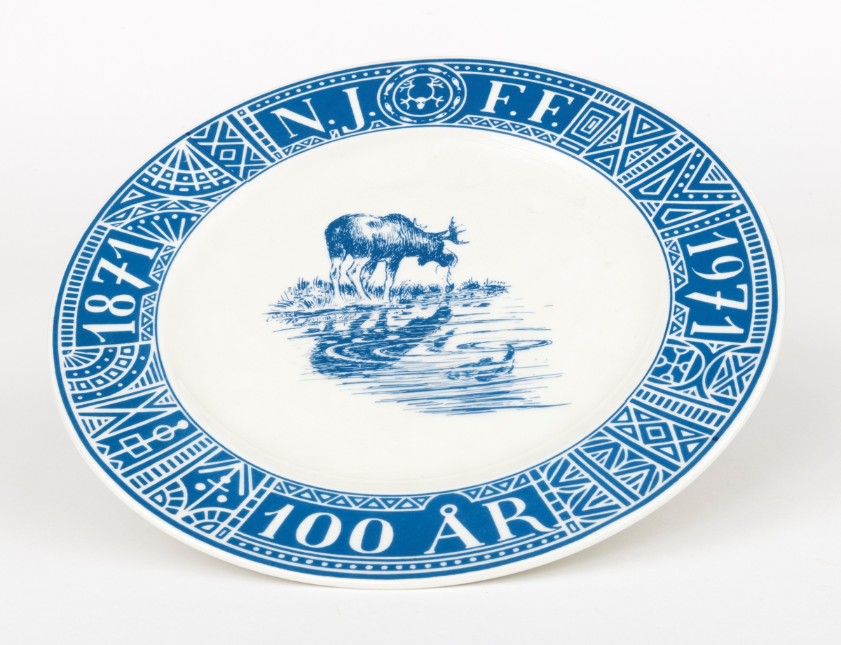 Tallerken, porodusert i forbindelse med Norges Jeger- og Fiskerforenings 100-årsjubileum i 1971. Det er en rund tallerken med 28,4 centimeters diameter. Den sentrale delen er forholdsvis plan, men med oppoverbuete sidekanter som danner ei skål med snaut 20 centimeters diameter. Utenfor dette partiet er det en 4,3 centimeter bred utoverskrånende kant. Tallerkenen er kvit, men har blå dekor. Sentralt i skåla har man gjengitt ei strektegning av en elg som slurper i seg vann og vannplanter i strandsona mot et skogstjern, der den speiles i vannflata. I vannet, og noe mindre framtredende, skimter vi en fisk som har skapt ringer på vannspeilet. Rundt ytterkanten av tallerkenen er det en slags bord som er blå med kvite streker. Her finner vi den jubilerende organisasjonens initialer, «N.J.F.F.», der de to første og de to siste bokstavene skilles av organisasjonens logo, et stilisert reinhode med gevir omgitt av en ring med stiliserte fisker. Også årstallene «1871» og «1971» og en påminnelse om den mellomliggende perioden «100 ÅR» som ble feiret med jubileum inngår i kantdekoren. På undersida av tallerkenen er det en sirkeformet vulst med ytre diameter på 15 centimeter som skulle sikre at tallerkenen sto støtt på et plant underlag. I denne vulsten er det to gjennombrutte hull for eventuell opphengshempe. Sentralt på undersida finner vi produsentens logo - ei stilisert steinøks med produsentens navn «STAVANGERFLINT» i en hesteskoform rundt skaftet. Under finner vi opphavslandet «NORWAY» på ei rett linje.

Dette er en tallerken som det naturligvis gikk an å spise middagsmat fra, eller kanskje til å servere småkaker på, men det var nok neppe med tanke på slike funksjoner den ble produsert. Tallerkenen var nok primært et utstillingsobjekt som skulle markere tilhøringhet til organisasjonen Norges Jeger- og Fiskerforbund og delaktighet i dens jubileumsfeiring. Hva man feiret framgår av en historisk artikkel som er gjengitt under fanen «Opplysninger».