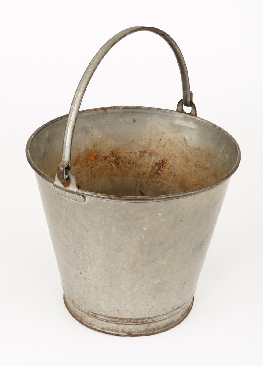 Bøtte av den typen det var vanlig å bære vann i. Bøtta er sveiset ihop av jernblikk. Den er rund, med en diameter som øker fra standflata (18,4 centimeter) til overkanten (27,1 centimeter). Høyden på sjølve beholderen er 23,4 centimeter, regnet fra underlaget til overkanten. I den nedre enden er det en forsterkende fals. Botnplata er noe nedoverbuket. Ved overkanten, diametralt plassert i forhold til hverandre, er det påsveiset «ører» med gjennombrutte hull for feste av bærehanken, som er buet i halvsirkelform. Den ene av disse er plassert over sveiseskjøten som binder plata i sideveggen sammen, og har dermed fungert som forsterkende element i tillegg til å være hankfeste. Hanken er lagd av 2,35 millimeter tjukt galvanisert jern. Den er 1,14 centimeter bred og har et U-formet tverrsnitt, der den runde sida er nedovervendt, slik at hanken ikke skulle gnage i fingrene på bæreren. Bøtta har noe rust i den innvendige botnen, men den er fortsatt tett. Den rommer drøyt 8 liter væske når den fylles breddfull.