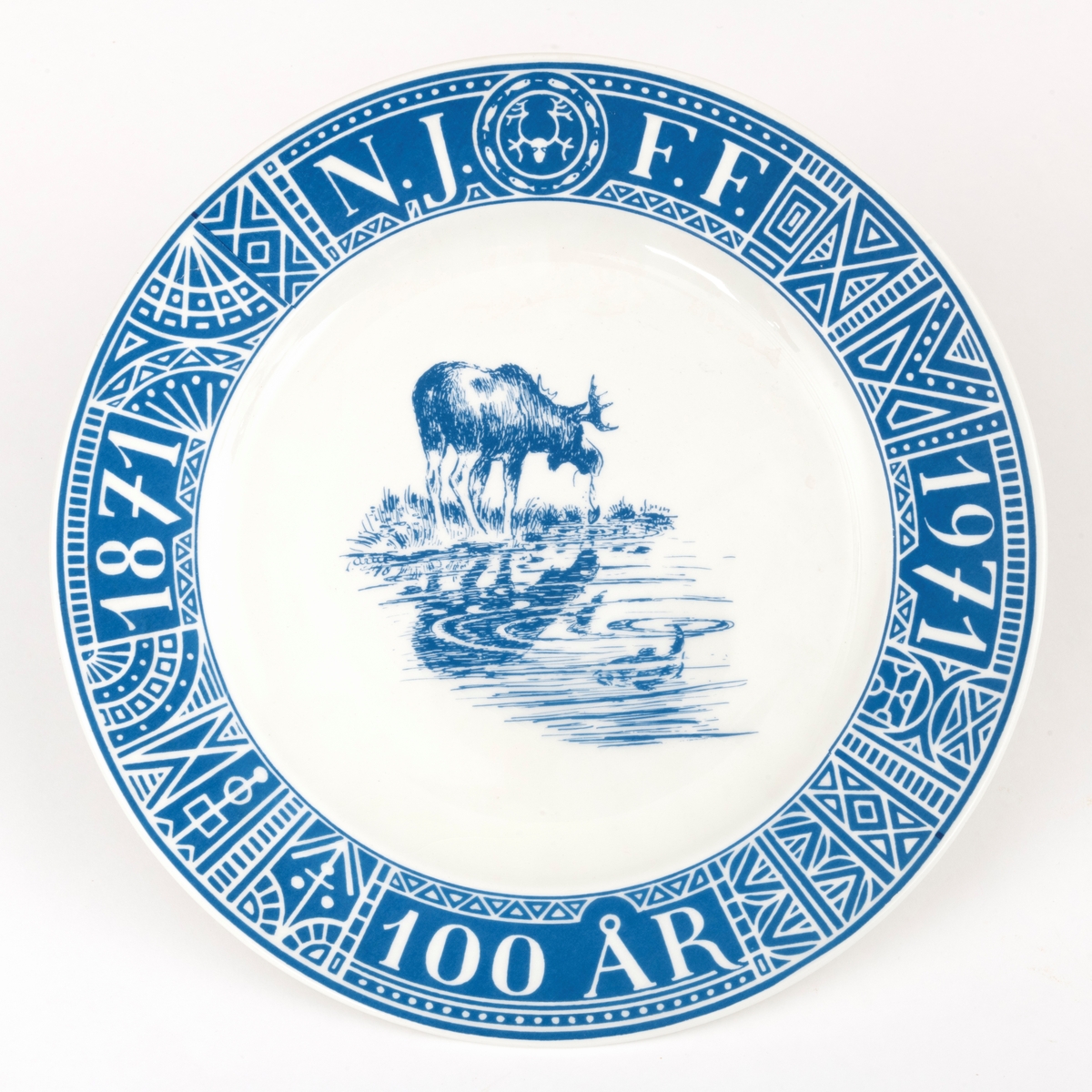Tallerken, porodusert i forbindelse med Norges Jeger- og Fiskerforenings 100-årsjubileum i 1971. Det er en rund tallerken med 28,4 centimeters diameter. Den sentrale delen er forholdsvis plan, men med oppoverbuete sidekanter som danner ei skål med snaut 20 centimeters diameter. Utenfor dette partiet er det en 4,3 centimeter bred utoverskrånende kant. Tallerkenen er kvit, men har blå dekor. Sentralt i skåla har man gjengitt ei strektegning av en elg som slurper i seg vann og vannplanter i strandsona mot et skogstjern, der den speiles i vannflata. I vannet, og noe mindre framtredende, skimter vi en fisk som har skapt ringer på vannspeilet. Rundt ytterkanten av tallerkenen er det en slags bord som er blå med kvite streker. Her finner vi den jubilerende organisasjonens initialer, «N.J.F.F.», der de to første og de to siste bokstavene skilles av organisasjonens logo, et stilisert reinhode med gevir omgitt av en ring med stiliserte fisker. Også årstallene «1871» og «1971» og en påminnelse om den mellomliggende perioden «100 ÅR» som ble feiret med jubileum inngår i kantdekoren. På undersida av tallerkenen er det en sirkeformet vulst med ytre diameter på 15 centimeter som skulle sikre at tallerkenen sto støtt på et plant underlag. I denne vulsten er det to gjennombrutte hull for eventuell opphengshempe. Sentralt på undersida finner vi produsentens logo - ei stilisert steinøks med produsentens navn «STAVANGERFLINT» i en hesteskoform rundt skaftet. Under finner vi opphavslandet «NORWAY» på ei rett linje.

Dette er en tallerken som det naturligvis gikk an å spise middagsmat fra, eller kanskje til å servere småkaker på, men det var nok neppe med tanke på slike funksjoner den ble produsert. Tallerkenen var nok primært et utstillingsobjekt som skulle markere tilhøringhet til organisasjonen Norges Jeger- og Fiskerforbund og delaktighet i dens jubileumsfeiring. Hva man feiret framgår av en historisk artikkel som er gjengitt under fanen «Opplysninger».